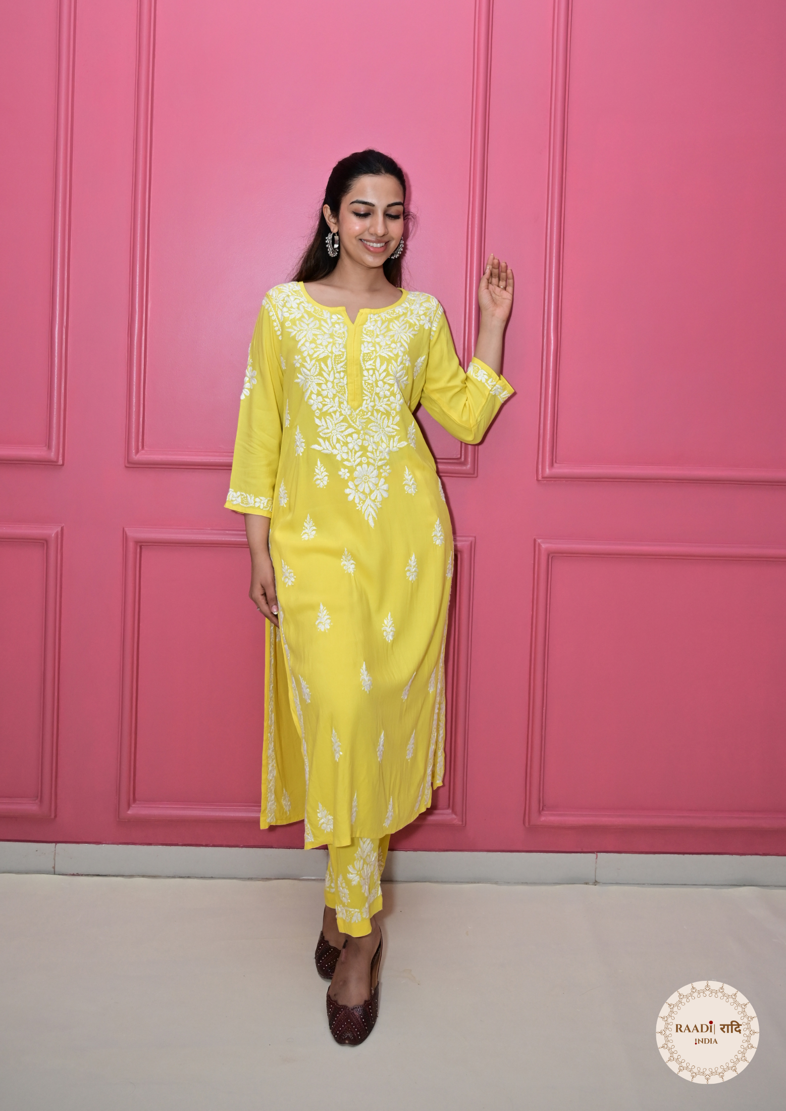 Woman in a yellow outfit posing against a pink wall