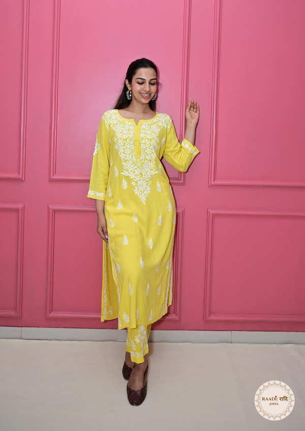 Woman in a yellow outfit posing against a pink wall
